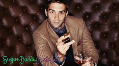 Hombre sonriente en un sillón de cuero con un vaso de whisky y una tarjeta de crédito.